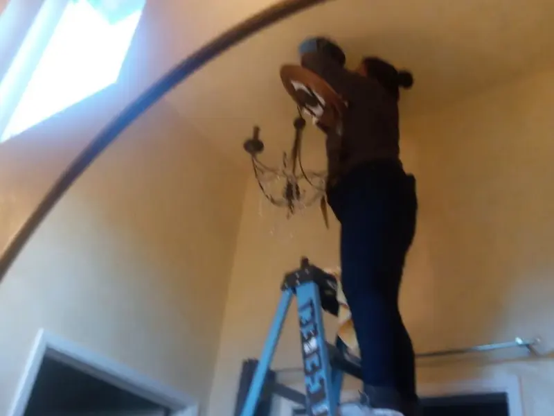 Electrician installing a chandelier in a Fox Chapel residence